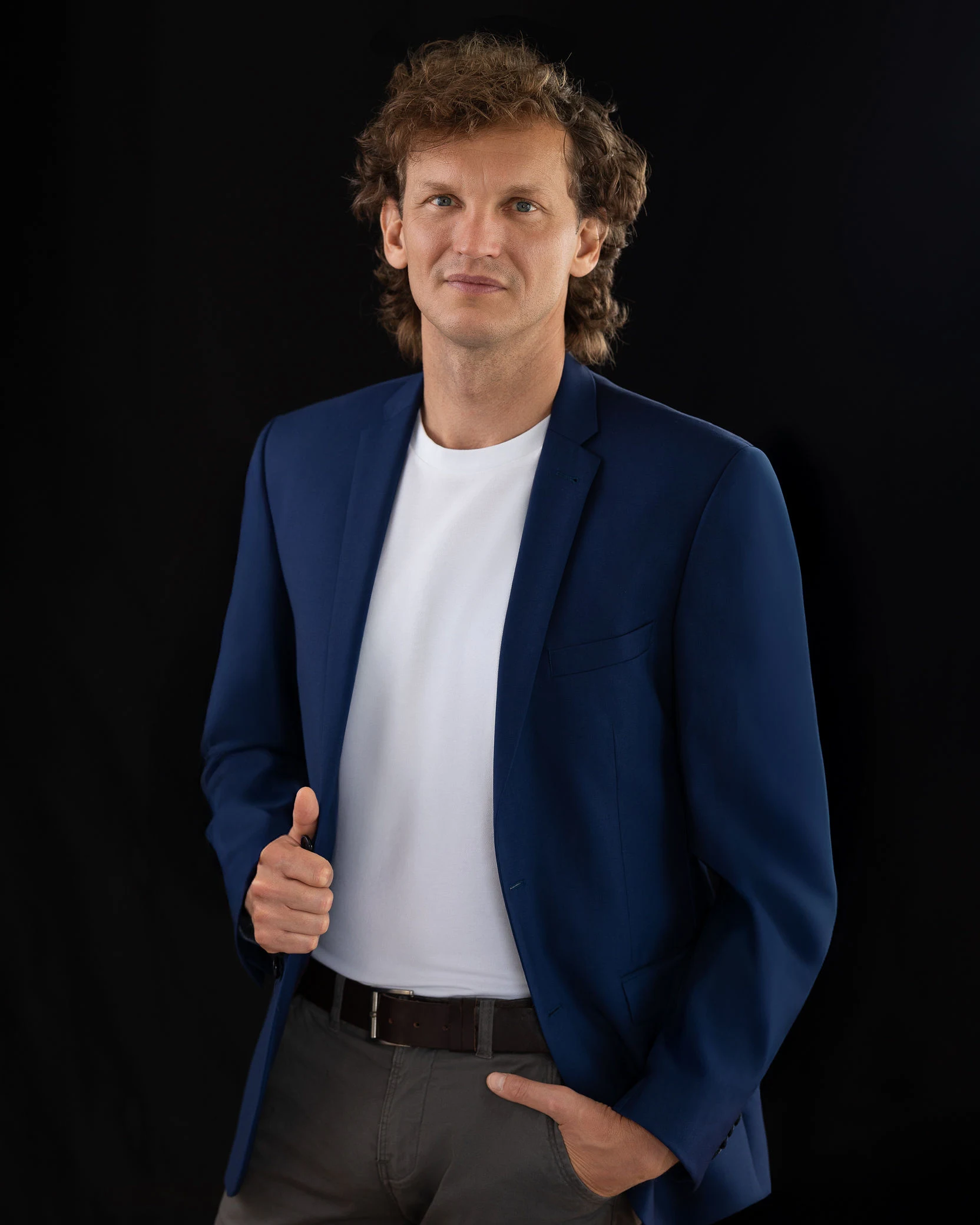 Krzysztof w granatowej marynarce na ciemnym tle.